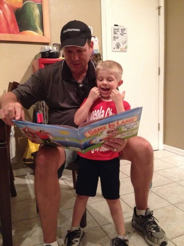 A father reading Same Is Lame aloud to his delighted young son